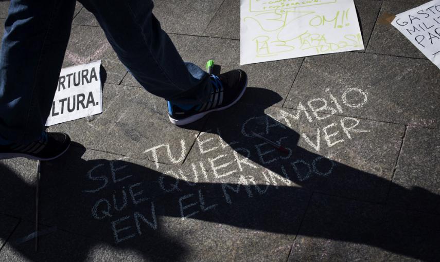 Una persona pasa ante una pintada en el suelo en la madrileña Puerta del Sol donde se celebra hoy el cuarto aniversario del movimiento 15M. EFE/Luca Piergiovanni