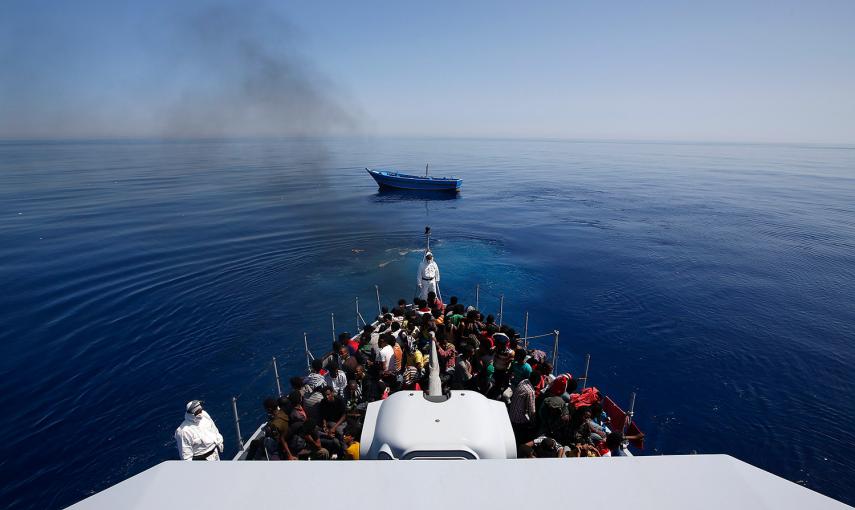 Un grupo de 300 africanos subsaharianos, sentado en un buque de la Policía Italiana de Finanazas, mientras su bote se aleja a la deriva frente a la costa de Sicilia.- ALESSANDRO BIANCHI (REUTERS)