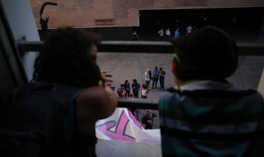 Dos activistas miran por la ventana del edificio que han okupado en el centro de Madrid.- JAIRO VARGAS