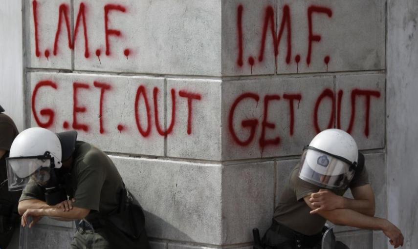 Dos agentes antidisturbios junto a dos pintadas contra el FMI. - REUTERS