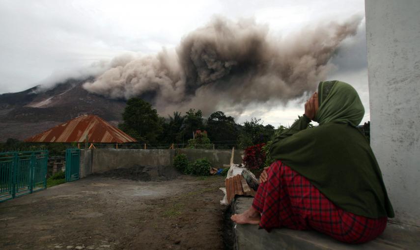 Una mujer observa mientras el Monte Sinabung lanza cenizas piroclásticas hoy, martes 16 de junio de 2015, desde la villa Kuta Tengah, en Karo, al norte de Sumatra./ EFE/Dedi Sahputra