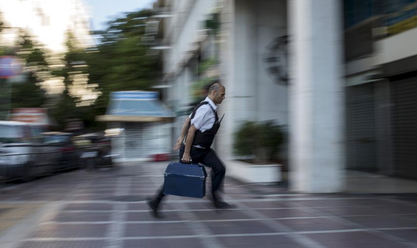 Un trabajador de seguridad lleva dinero a una sucursal del Banco Nacional en Atenas. REUTERS / Marko Djurica
