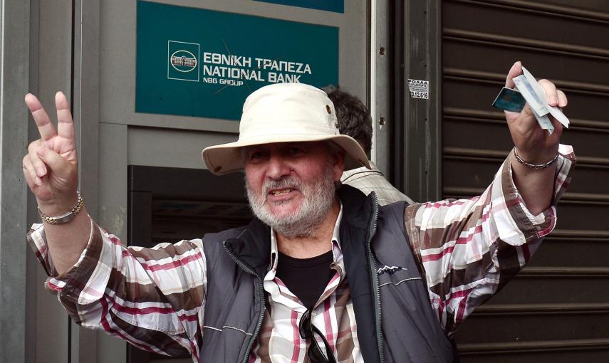 Un hombre celebra ante los medios de comunicación que ha sacado los 60 euros diarios de los que puede disponer cada ciudadano en Grecia tras decretarse el corralito.- AFP PHOTO / Louisa GOULIAMAKI