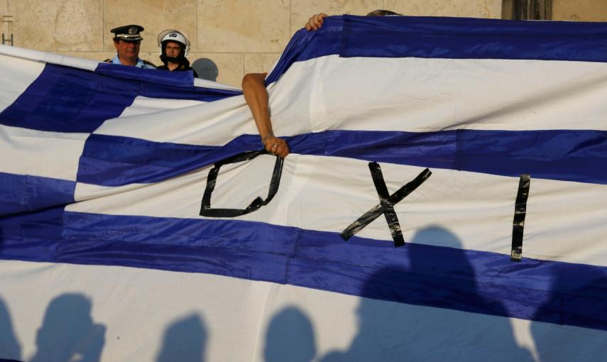 Los manifestantes sostienen una bandera griega junto a agentes de la policía antidisturbios en frente del edificio del Parlamento durante una manifestación contra la austeridad y por el 'NO' en el referéndum en Atenas.- REUTERS / Yannis Behrakis