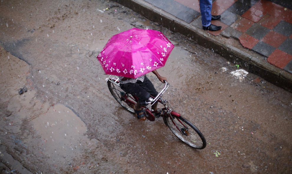 Un hombre rueda bajo la lluvia del monzón en Daca, Bangladesh, hoy 9 de julio de 2015 La vida cotidiana se ve perturbada por las continuas lluvias en el país. EFE/Abir Abdullah