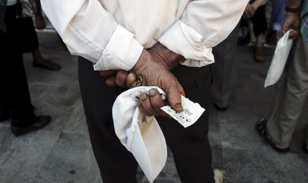 Un pensionista espera con su ticket de prioridad para recibir su pensión en una sucursal de National Bank en Atenas, Grecia, hoy. REUTERS/Alkis Konstantinidis