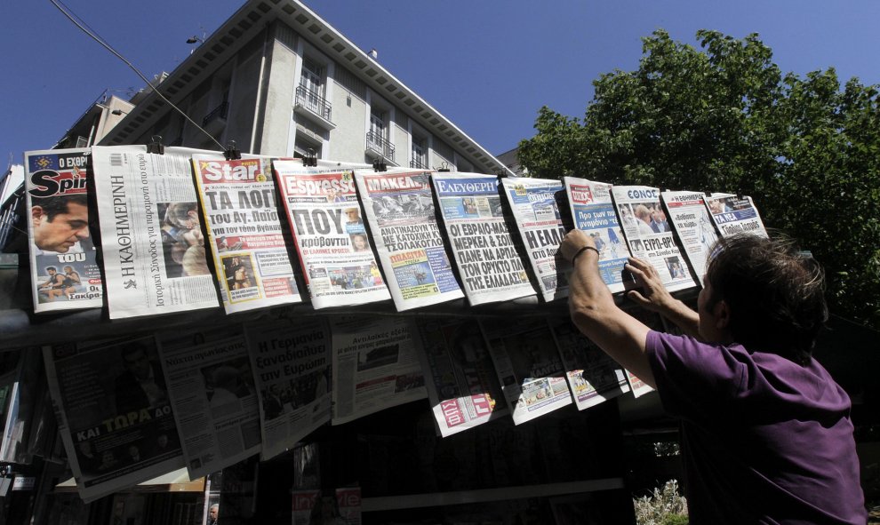 Un ciudadano lee las portadas de los diarios en un quiosco en el centro de Atenas (Grecia) hoy. Los líderes de la eurozona sortearon el abismo de la salida de Grecia del euro y de que ello arrastrara al resto de la eurozona a un terreno desconocido con un
