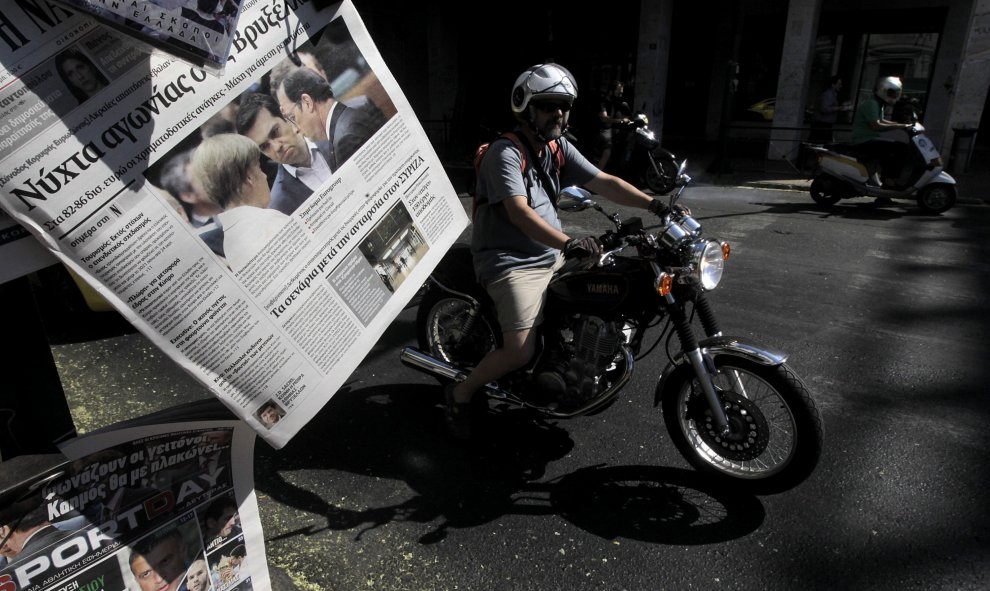 Un motorista pasa junto a un quiosco de prensa en el centro de Atenas (Grecia) hoy. EFE/Orestis Panagiotou