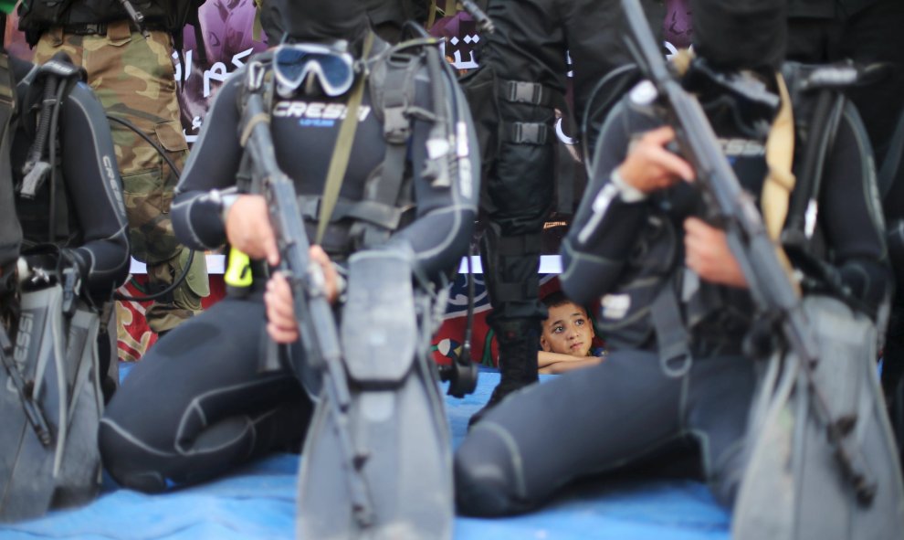 Un niño palestino observa miembros de la unidad marítima de al-Qassam participar en un desfile anti-israelí en Rafah, en el sur de la Franja de Gaza 13 de julio de 2015. REUTERS / Ibraheem Abu Mustafa