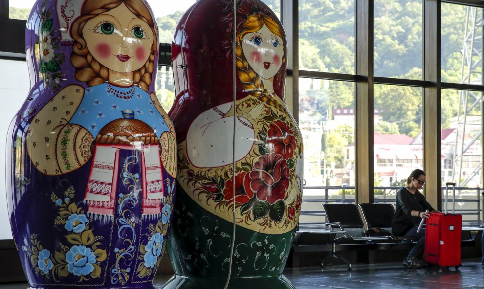 Una mujer se sienta junto a las muñecas matryoshka gigantes dentro de una terminal del aeropuerto de Sochi en Adle , Rusia, 13 de julio de 2015. Rusia será la sede la Copa Mundial de la FIFA en 2018. REUTERS / Maxim Shemetov