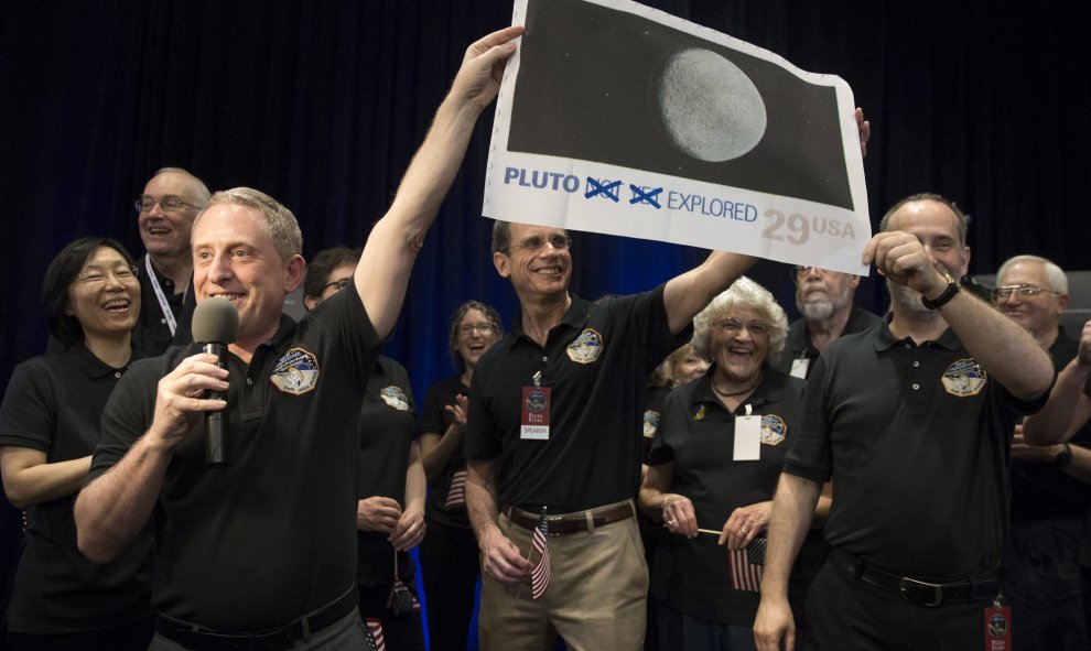 El investigador principal del programa New Horizons, Alan Stern (i), celebra que la nave espacial estadounidense "New Horizons" ha logrado aproximarse a unos 12.500 kilómetros (7.800 millas) de Plutón, lo más cerca que se ha estado nunca del desconocido p