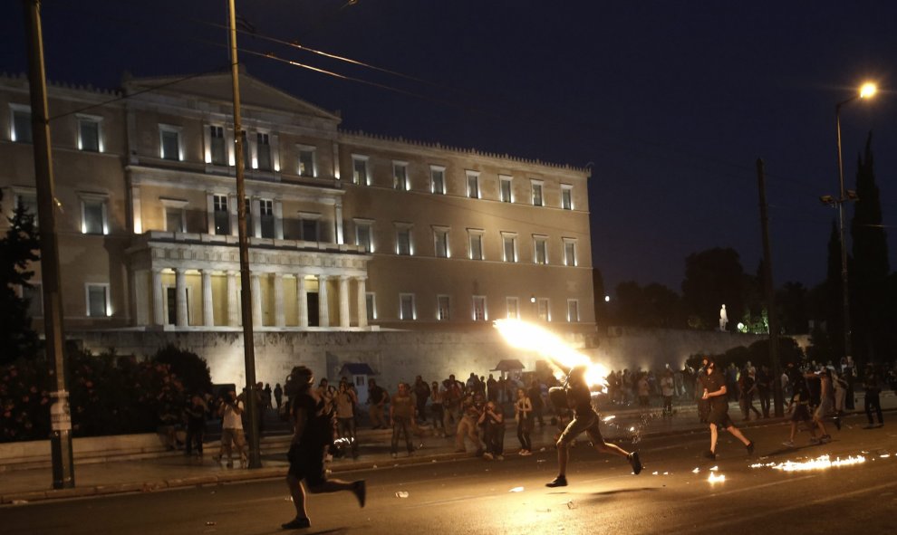 Un manifestante lanza a la policía un cóctel molotov a la policía frente al edificio del Parlamento, en plena Plaza Syntagma. EFE/YANNIS KOLESIDIS