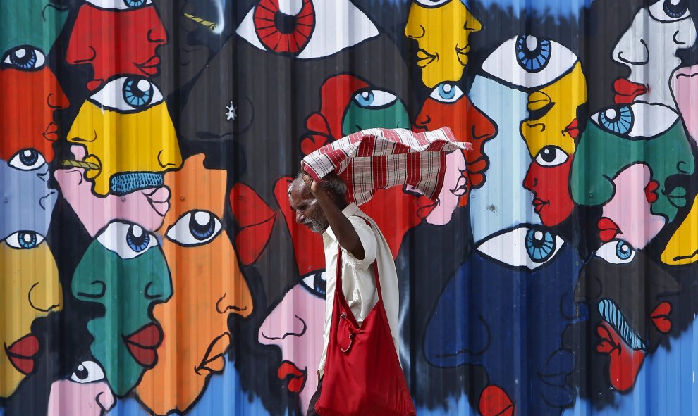 Un hombre se coloca el pañuelo al pasar al lado de un muro en una calle de Nueva Delhi, India. 16 de julio, 2015. REUTERS/Anindito Mukherjee