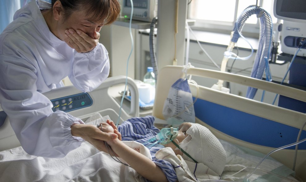 Hanhan, de tres años, después de una cirugía para implantar tres piezas de titanio para reemplazar su cráneo, con su tía, que llora mientras sostiene su mano en un hospital en Changsha, provincia de Hunan, China, 15 de julio 2015. REUTERS/Stringer