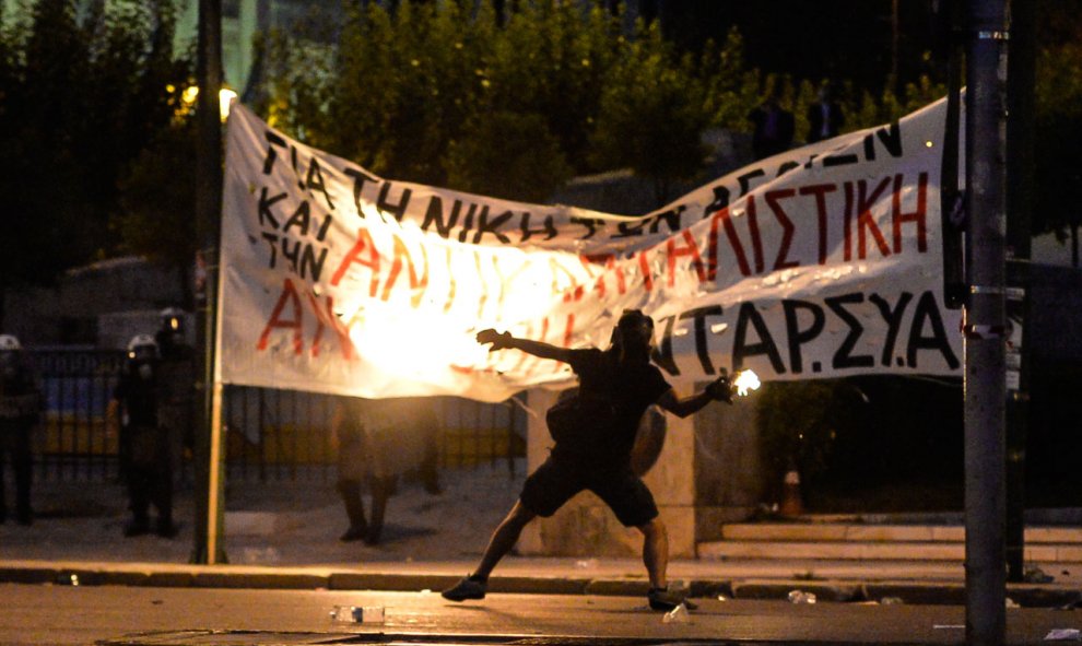 Un manifestante lanza un cóctel molotov hacia los antidisturbios durante los enfrentamientos frente al Parlamento griego en Atenas anoche, el 15 de julio de 2015. AFP PHOTO / ANDREAS SOLARO