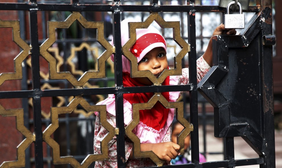 Una niña pide en las puertas de una mezquita en el último día del Ramadán, en Kuala Lumpur, Malasia, 16 de julio de 2015. REUTERS / Olivia Harris.