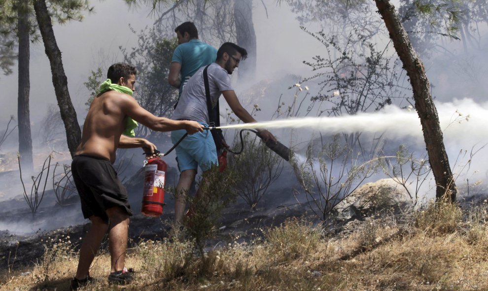 Varios voluntarios intentan extinguir las llamas en el suburbio de Karea en Atenas (Grecia) hoy. Un gran incendio originado esta madrugada en la región griega de Laconia, en el sur del Peloponeso, ha obligado a evacuar tres pueblos y dos campamentos infan