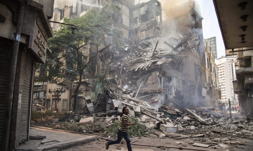 Un hombre corre junto al un edificio en llamas en el distritito de Fagala, en el centro de El Cairo (Egipto) hoy, 20 de julio de 2015. El incendio, que habría empezado en un almacén de papel, se extendió a los edificios aledaños y provocó un fuego masivo