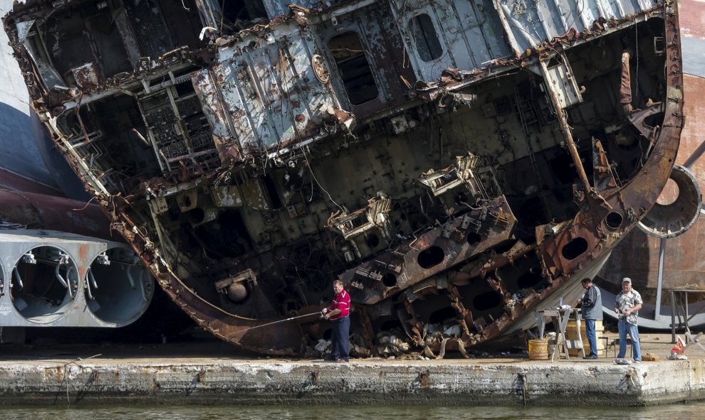 Varios hombres pescan en frente de barcos destrozados en la base de la flota rusa en Baltiysk, en la región de Kaliningrado, Rusia. Kaliningrado será una sede de la Copa Mundial 2018. REUTERS / Maxim Shemetov