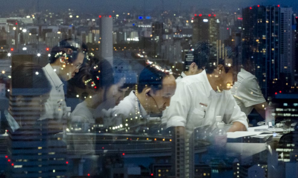 Se reflejan los reporteros en una ventana con vistas a Tokio anoche mientras trabajaban después de una rueda de prensa en la sede de Toshiba el 21 de julio de 2015. El presidente ejecutivo de Toshiba Corp renunció su puesto el martes después de verse invo