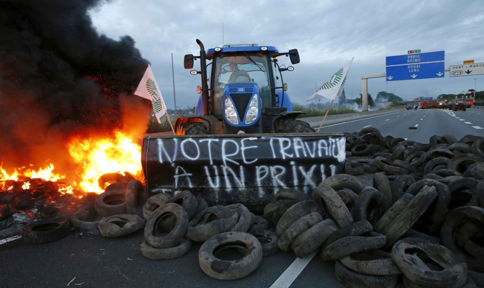Un ganadero francés utiliza su tractor para alimentar con llantas una barricada y bloquear la autopista A1 Lille-París./ REUTERS. Pascal Rossignol