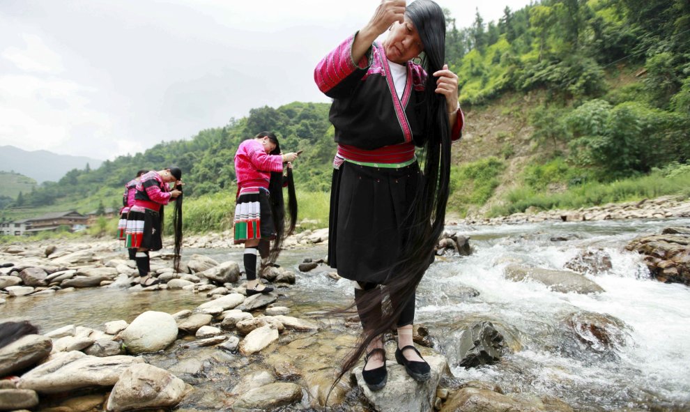 Mujeres de la minoría étnica Yao se cepillan el pelo cerca de un arroyo, en la aldea de Huangluo de Guilin, Región Autónoma Zhuang de Guangxi, China, 23 de julio de 2015. El pueblo, conocido por el largo cabello de sus residentes femeninos, atrae a unos 8