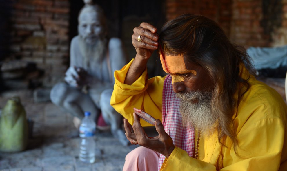 Un sadhu (hombre santo) se colorea la cara con una pasta especial en el templo de Pashupatinath en Katmandú, el 27 de julio de 2015. Decenas de sadhus viven alrededor del templo para dedicar su vida a Shiva, el dios hindú de la destrucción. AFP PHOTO / Pr