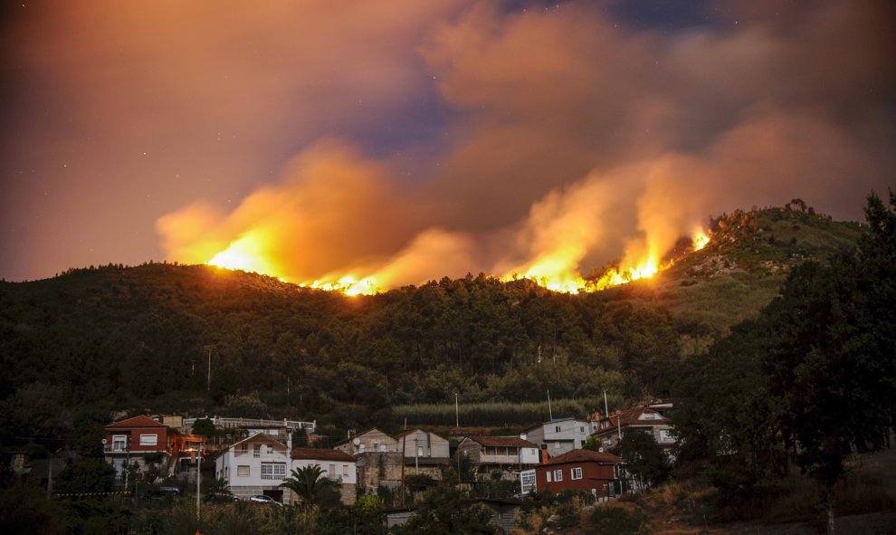 Vista del pueblo de Untes rodeado por las llamas del incendio forestal registrado en las afueras de la ciudad de Ourense, que ha ido adquiriendo grandes dimensiones y ha obligado a decretar el nivel dos de riesgo, ya que ha rodeado viviendas, ha afectado