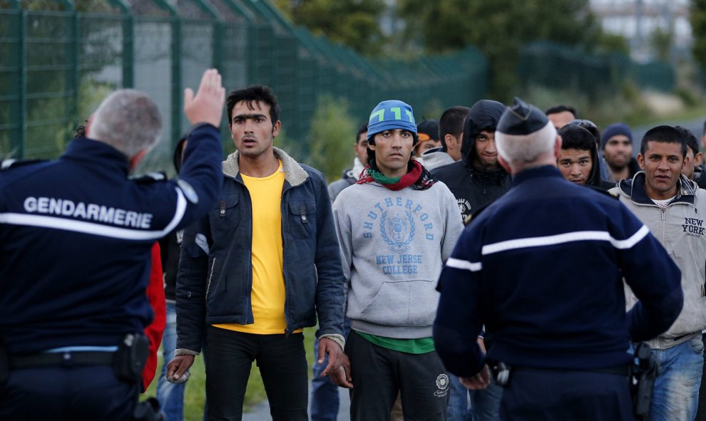 Policía para a inmigrantes que caminan para tratar de llegar al tren que los conduce a Inglaterra. EFE/YOAN VALAT