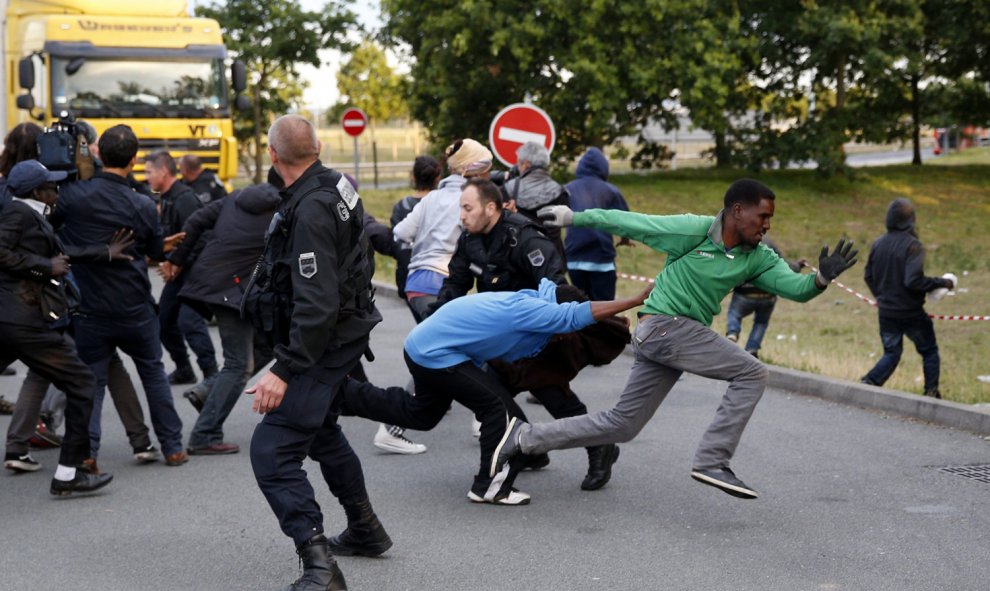 Varios migrantes escapan de las autoridades francesas antes de intentar tomar un tren en su ruta hacia Inglaterra, en Calais (Francia). EFE