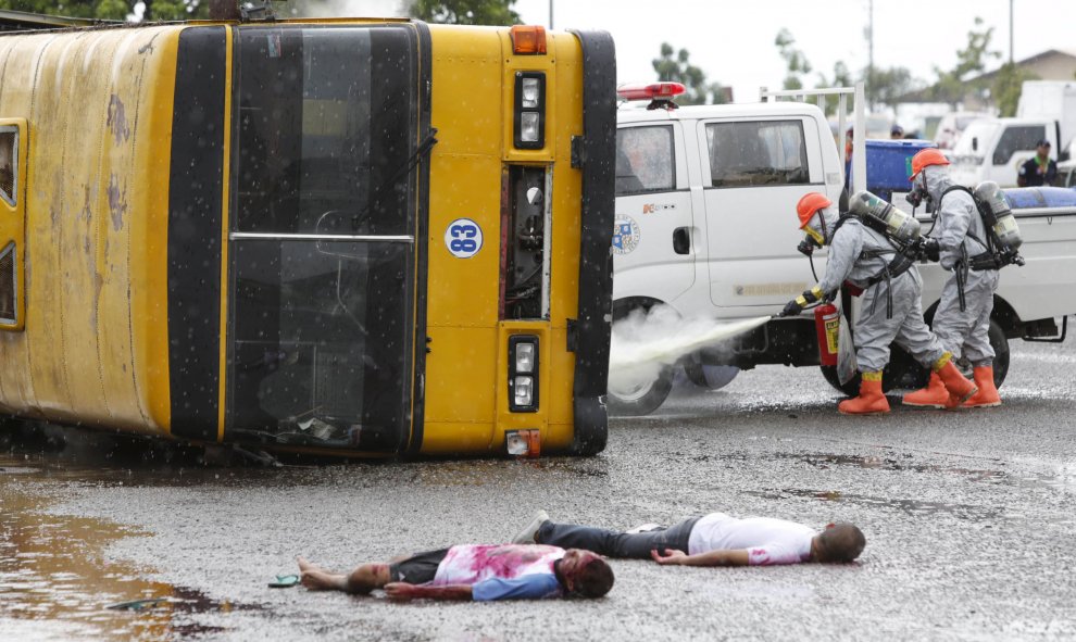 Los servicios de bomberos y rescate, vestidos con trajes especiales, realizan un simulacro con "heridos" al lado de un autobús, mientras apagan un incendio químico en la ciudad de Cebú, Filipinas, 31 de julio de 2015. REUTERS / Charlie Saceda