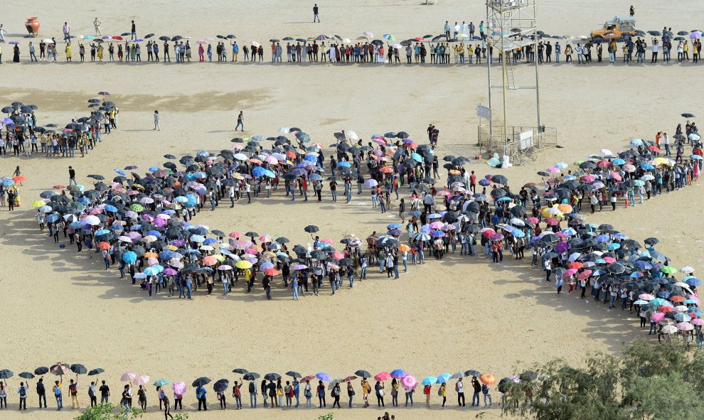 Estudiantes indios forman una 'cinta de conciencia', con más de 2.500 sombrillas y crean un mosaico en una playa en Mumbai, el 31 de julio de 2015. Intentan establecer un nuevo récord del mayor número de paraguas en un mosaico con el objetivo de apoyar a