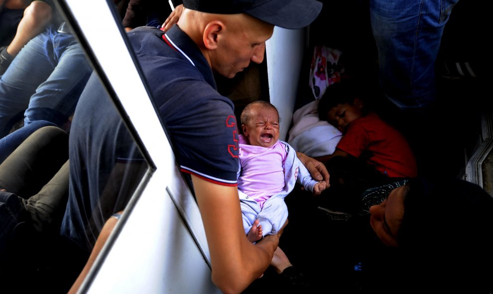 Un emigrante de Alepo, Siria, con su bebé de 30 días de edad en un tren que pasa por Macedonia. Tras ir a pie hasta la frontera de Macedonia, decenas de miles de emigrantes se suben al tren en la estación de Gevgelia para viajar 200km hacia el norte. REU