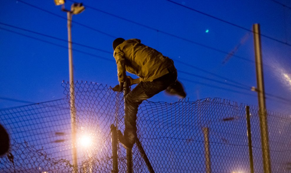 Un inmigrante escala una valla de acceso al túnel del Canal de La Mancha, en Frethun, al norte de Francia.- AFP PHOTO / PHILIPPE HUGUEN