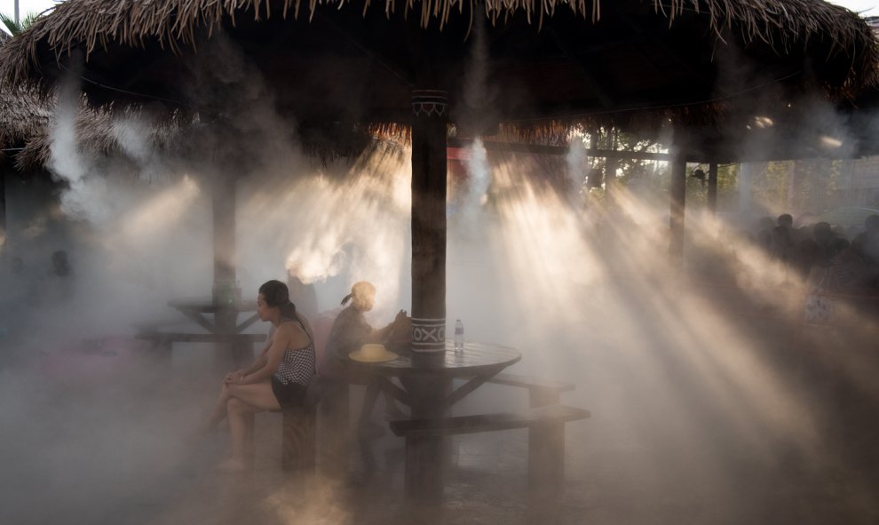 La gente se refresca debajo de un aspersor en un parque acuático en Shanghai.- AFP PHOTO / JOHANNES EISELE