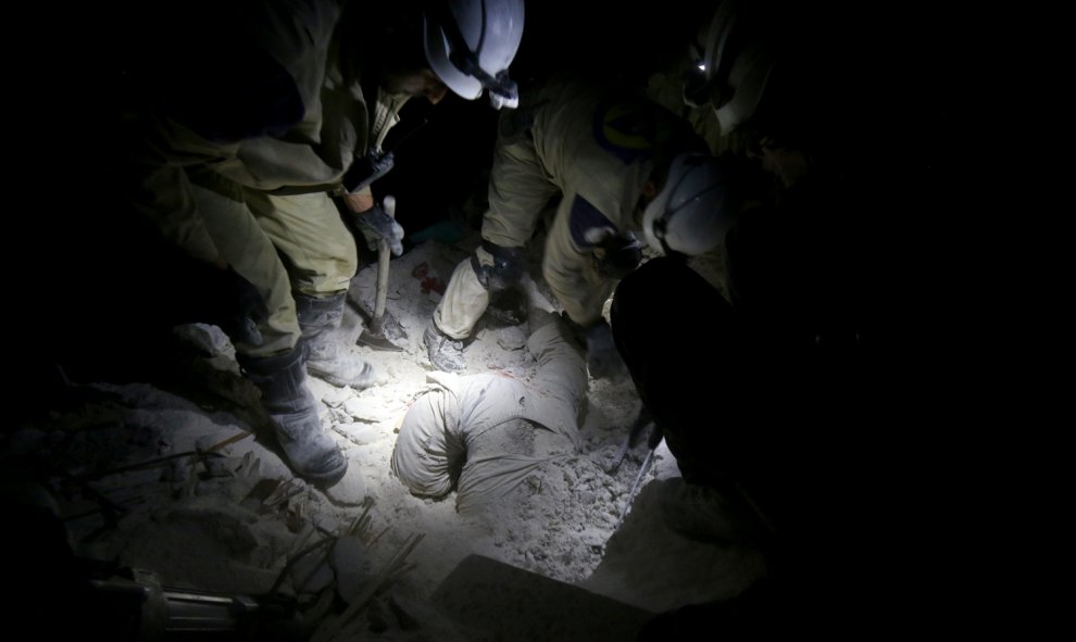 Miembros de los servicios de emergencia sirios tratan de sacar un cuerpo de entre los escombros tras el impacto de una misill disparado por las fuerzas gubernamentales sirias sobre una zona residencial en el barrio de Sheikh Khodr de Alepo.-ZEIN AL-RIFAI