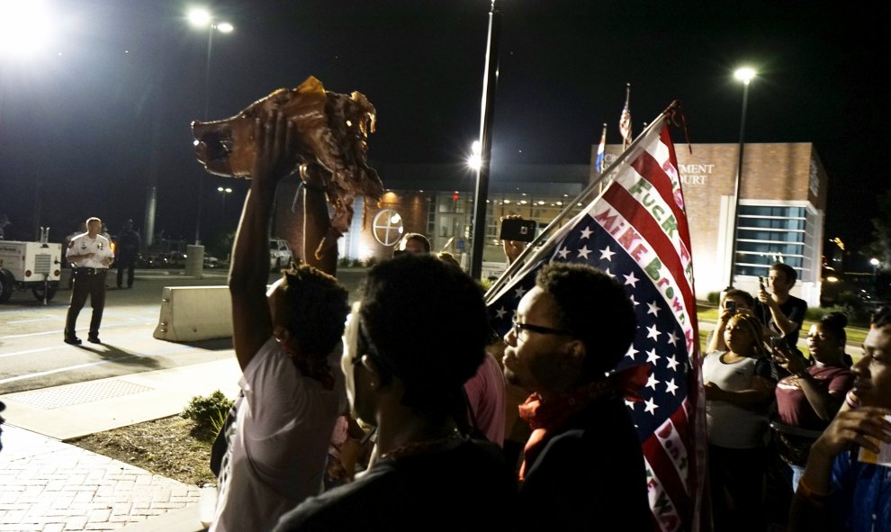 Manifestantes sostienen una cabeza de cerdo de un asado de cerdo fuera del departamento de policía de Ferguson. REUTERS / Rick Wilking