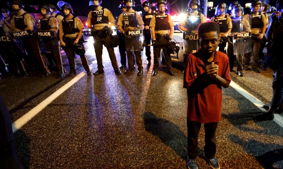 Amarion Allen, de 11 años, se sitúa frente la policía poco antes de que un policia disparase a unos manifestantes en Ferguson, Missouri, anoche, 9 de agosto 2015. Dos personas fueron disparadas en medio de un enfrentamiento nocturno entre los antidisturbi
