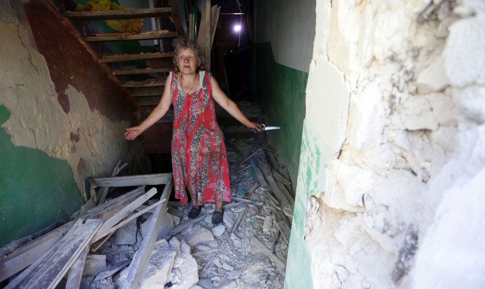 Una mujer dentro de su casa destruida como consecuencia de los bombardeos entre las fuerzas ucranianas y los separatistas pro-rusos el 10 de agosto de 2015, de la aldea Golmovsky, región de Donetsk. ALEKSEY FILIPPOV / AFP