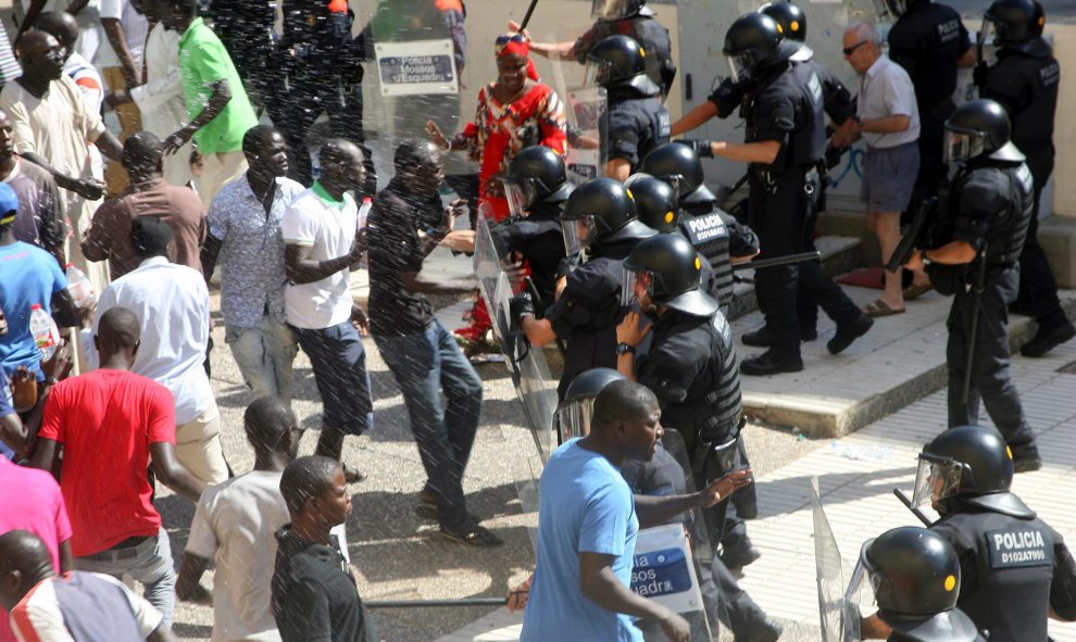 La policía carga contra los compañeros del inmigrante fallecido, que intentaban evitar el traslado de su cuerpo. EFE/Jaume Sellart