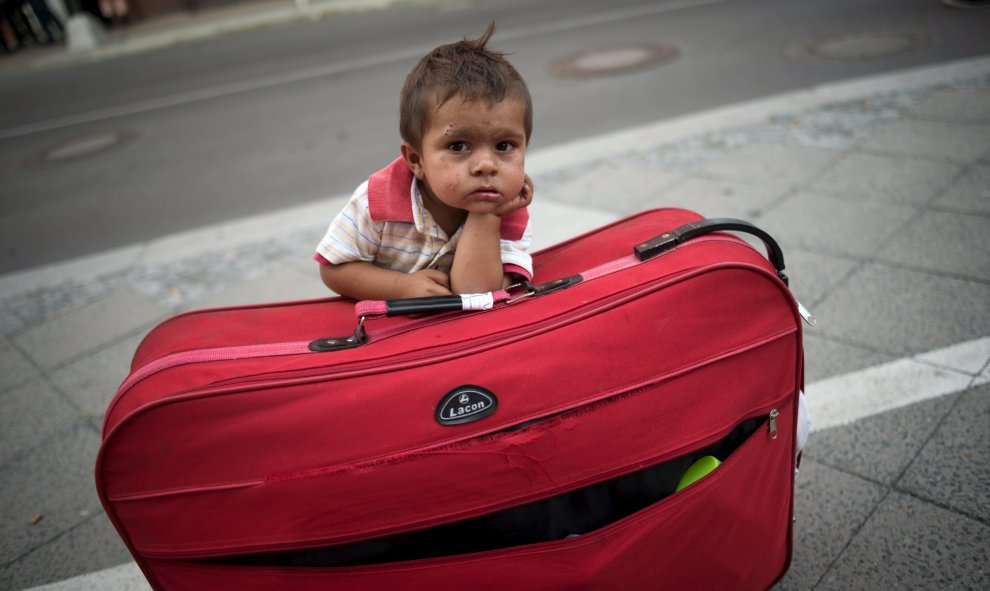 Un niño espera a sus padres apoyado en su maleta al salir de la Oficina Estatal de Salud y Asuntos Sociales de Berlín con otros refugiados recién llegados que esperaron todo el día para solicitar el asilo en Berlín. REUTERS / Stefanie Loos