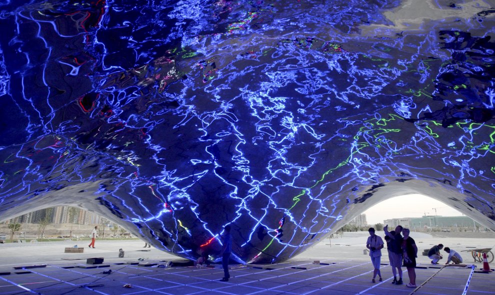 Gente mirando la prueba de iluminación dentro de una nueva escultura con forma de burbuja gigante de petróleo, en un complejo turístico construido cerca del primer pozo de perforación del yacimiento Karamay, Región Autónoma Uigur, China. REUTERS / Stringe