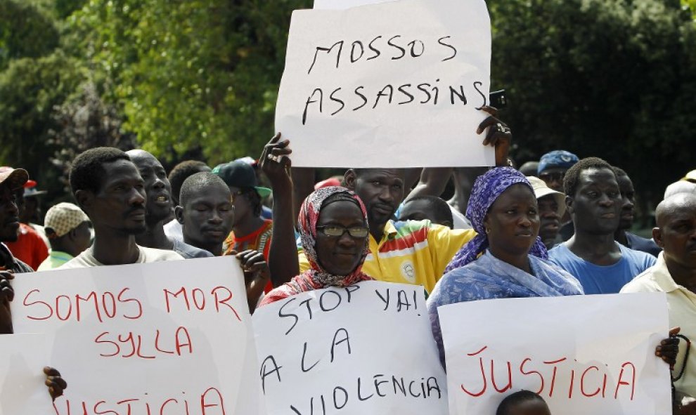Inmigrantes senegaleses muestran pancartas contra la los Mossos D'esquadra en la manifestació en Salou para protestar por la muerte de un compatriota en una operación contra el 'top manta'. AFP PHOTO / QUIQUE GARCIA