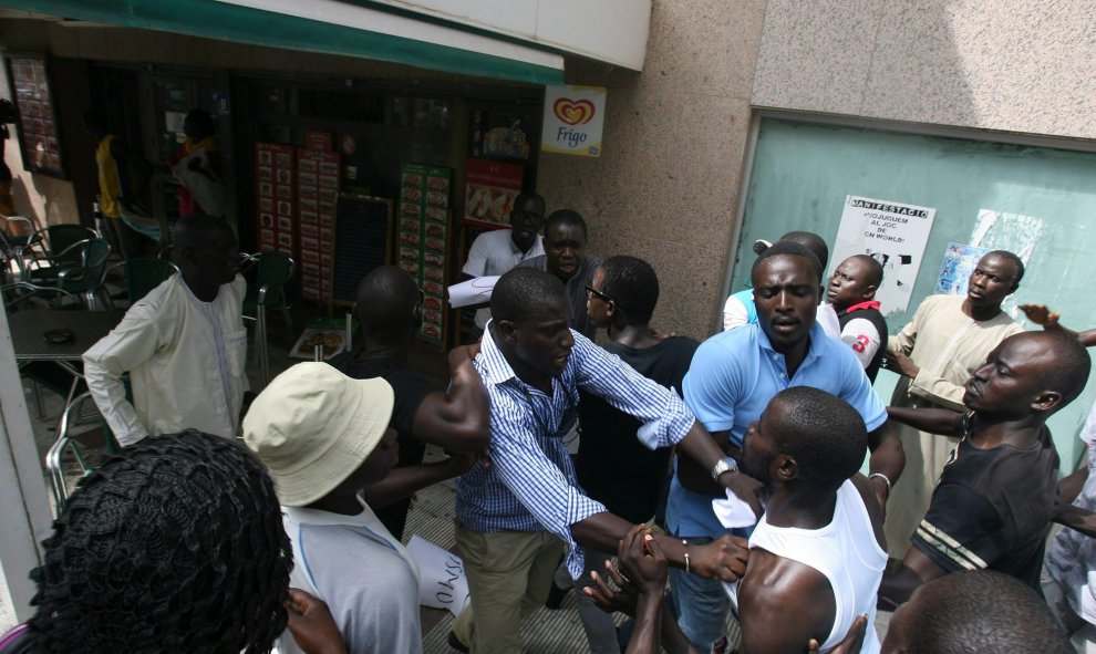 Ibrahim Sylla, centro con camisa a cuadros, y hermano del senegalés muerto al huir de los Mossos durante una operación contra la venta ilegal ambulante, controla a unos exaltados que han irrumpido en un bar cuando un cliente ha hecho un comentario inaprop