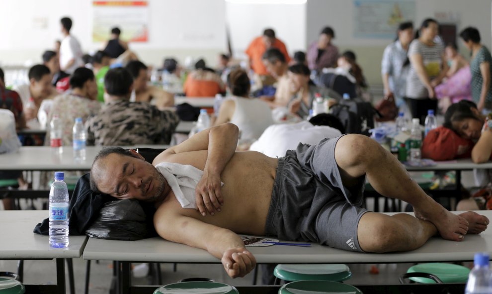 Un hombre descansa en el comedor de la escuela donde han sido realojados los afectados. REUTERS
