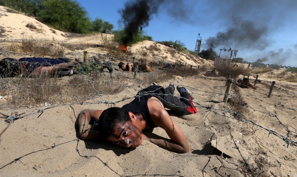 Un joven palestino bajo un alambre de púas durante un ejercicio de estilo militar en un campamento de verano organizado por el movimiento de la Yihad Islámica, en Khan Younis, en el sur de la Franja de Gaza, 13 de agosto de 2015. REUTERS / Ibraheem Abu Mu