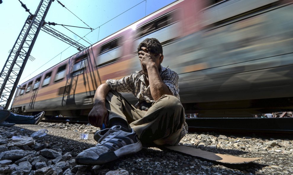 Un inmigrante exhausto y frustrado tras no poder conseguir una plaza en un tren que se dirige a la frontera con Serbia en la estación de tren de Gevgelija (Macedonia) hoy, 13 de agosto de 2015. EFE/Georgi Licovski