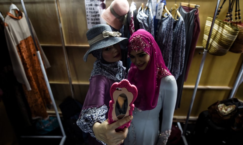 Modelos haciéndose selfies mientras esperan el backstage antes del inicio de la pasarela de moda islámica durante la semana de moda de Kuala Lumpur 2015. AFP PHOTO / MANAN VATSYAYANA