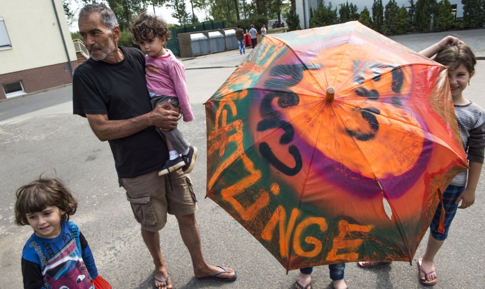 Un joven sirio solicitante de asilo lleva un paraguas decorado con las palabras: " Un corazón para los refugiados " en el centro " Zentrale Aufnahmestelle für Asylbewerber ", en Eisenhuettenstadt, al este de Alemania. JOHN MACDOUGALL / AFP