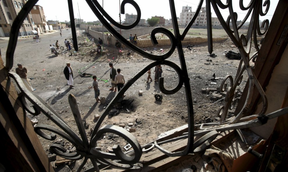 Se ven peatones desde una ventana de una casa, cerca del sitio del coche bomba que explotó el jueves en la capital de Yemen, Saná 14 de agosto de 2015. No hubo víctimas de la explosión. REUTERS / Mohamed al- Sayaghi